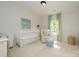 Sunlit bedroom with neutral carpet, a cozy chair, and a white baby crib at 5916 Rexwood Pl, Charlotte, NC 28210