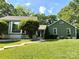 Charming home featuring a lush green lawn, mature trees, and beautiful exterior details at 5916 Rexwood Pl, Charlotte, NC 28210