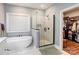 Bright bathroom featuring a standalone tub, a frameless shower with white tiles, and a doorway to a walk-in closet at 604 Airport Rd, Kannapolis, NC 28081