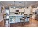Open kitchen with a center island featuring barstool seating, white cabinets with modern appliances, and wooden flooring at 604 Airport Rd, Kannapolis, NC 28081