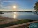 Beautiful view of the sun reflecting off the calm lake, with a beach and grassy area in the foreground at 657 Portside Dr, Davidson, NC 28036