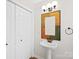 Bathroom featuring a pedestal sink, white walls, wood-look tile and a decorative mirror at 6647 Vlosi Dr, Charlotte, NC 28226