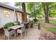 Inviting backyard patio features a dining set, grill, and access to a lush lawn and mature trees at 6718 Summerlin Pl, Charlotte, NC 28226