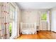 Bedroom room featuring hardwood floors, crib, and large windows for natural light at 6718 Summerlin Pl, Charlotte, NC 28226