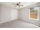 Carpeted bedroom with ceiling fan, window, and closet with double doors at 6849 Blake Brook Dr, Concord, NC 28025