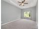 Main bedroom with ceiling fan, neutral colors, carpet, and large window with a view of the fenced-in backyard at 6849 Blake Brook Dr, Concord, NC 28025