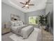 Staged main bedroom with neutral colors, ceiling fan, carpet, and large window with a view of the green front yard at 6849 Blake Brook Dr, Concord, NC 28025