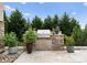 Outdoor kitchen featuring a built-in grill, stone surround, and a lush backdrop of trees and greenery at 767 Pinnacle Dr, Iron Station, NC 28080