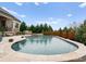 Inviting in-ground pool with a travertine surround, waterfall, and lush landscaping at 767 Pinnacle Dr, Iron Station, NC 28080