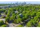 Aerial view of a tree-lined property, in front of the Charlotte skyline, surrounded by lush greenery at 974 Queens Rd, Charlotte, NC 28207