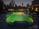 Beautiful in-ground pool illuminated with vibrant yellow lights, enhancing the nighttime ambiance at 106 Wrangler Dr, Mooresville, NC 28115