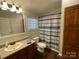 Well-lit bathroom with vanity, cabinet storage, toilet, and a shower with blue-striped curtain at 116 Dove Ln, New London, NC 28127