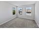 Bright bedroom featuring three windows and neutral-toned carpet at 11933 Silverheel Ln, Huntersville, NC 28078