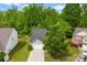Aerial view of house with a one-car garage, driveway, and a well-maintained lawn, surrounded by lush trees at 1457 Mandy Place Ct, Charlotte, NC 28216