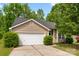 Attached two-car garage with a light beige facade and mature landscaping in the front yard at 1457 Mandy Place Ct, Charlotte, NC 28216