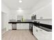 Bright, modern kitchen featuring white cabinets, stainless steel appliances, and black countertops at 1457 Mandy Place Ct, Charlotte, NC 28216