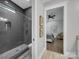 Modern bathroom featuring a tiled walk-in shower and view into main bedroom with ceiling fan at 1579 Sunset Pointe Dr, Salisbury, NC 28146