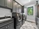 Well-lit laundry room featuring gray cabinetry, granite counters, washer, dryer, and herringbone floors at 1579 Sunset Pointe Dr, Salisbury, NC 28146