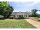 Inviting single-story home with lush green lawn, mature trees, and a cozy facade under a clear blue sky at 244 Whitesides Rd, Bessemer City, NC 28016