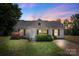 Charming single-story home with well-maintained lawn and landscaping, including flowering shrubs, under a colorful dusk sky at 244 Whitesides Rd, Bessemer City, NC 28016