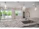 Kitchen island with granite countertop, stainless steel sink, and modern faucet with view to an outdoor patio at 286 Hemlock Bluff Ct, Denver, NC 28037