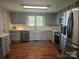 Well-lit kitchen with stainless steel appliances, gray cabinets and hardwood floors at 3100 Wallace Rd, Midland, NC 28107