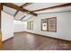 Living room with exposed beams, windows and wood floors offers ample natural light and architectural interest at 4815 Rifle Range Rd, Conover, NC 28613