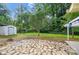 Spacious backyard featuring a stone patio, lush greenery, and storage shed at 6558 Covecreek Dr, Charlotte, NC 28215