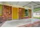 Close up of the entryway and brick facade, showing a yellow door, white columns, and green shutters at 6558 Covecreek Dr, Charlotte, NC 28215