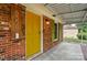 Close up of the entryway and brick facade, showing a yellow door, white columns, and green shutters at 6558 Covecreek Dr, Charlotte, NC 28215