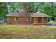 Charming brick home with a covered porch, yellow front door, green shutters, and mature landscaping at 6558 Covecreek Dr, Charlotte, NC 28215