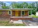 Inviting brick home with covered front porch, yellow front door, and well-maintained landscaping at 6558 Covecreek Dr, Charlotte, NC 28215