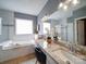 Well-lit bathroom with dual sinks, granite countertops, soaking tub, tile surround, and glass-enclosed shower at 7642 Horseshoe Creek Dr, Huntersville, NC 28078