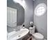 Cozy powder room featuring gray walls, modern fixtures, round window and hardwood floors at 7642 Horseshoe Creek Dr, Huntersville, NC 28078