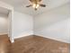 A spacious empty bedroom showing hardwood floors, ceiling fan and light, and a view of the hall at 7642 Porrera St, Charlotte, NC 28214