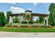 Community entrance sign surrounded by colorful flowers and greenery, set against a blue sky at 7642 Porrera St, Charlotte, NC 28214