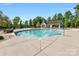 Community pool with a clear blue water, clubhouse, and lounge seating surrounded by trees at 7642 Porrera St, Charlotte, NC 28214