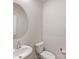 Well-lit powder room with a round mirror, single sink, and elongated toilet in a neutral color scheme at 7642 Porrera St, Charlotte, NC 28214