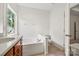 Well-lit bathroom with soaking tub, large window, neutral tile and traditional wood cabinets at 8120 Calistoga Ln, Waxhaw, NC 28173
