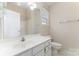 Well-lit bathroom featuring a white vanity, toilet, and a shower with neutral wall tile at 827 Gentlewinds Ct, Fort Mill, SC 29708