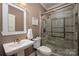 Bathroom featuring tiled shower with glass door, pedestal sink, and neutral decor at 900 Springwood Dr, Waxhaw, NC 28173