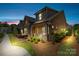 Stunning exterior view of a brick home with a charming porch, illuminated by the warm glow of dusk at 9319 Highclere Ct, Matthews, NC 28105