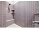 Modern shower with stylish gray tile, built-in shelving, and sleek fixtures offers a spa-like experience at 9319 Highclere Ct, Matthews, NC 28105