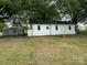 Back exterior of a single-story home featuring a spacious yard and detached storage buildings at 135 Hendren Ln, Hiddenite, NC 28636