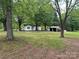 Quaint white home nestled among mature trees on a spacious lot, offering a serene and private setting at 135 Hendren Ln, Hiddenite, NC 28636