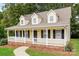 Low angle view of a yellow home with front porch and black door, surrounded by lush green trees at 1930 Manning Pl, Rock Hill, SC 29730