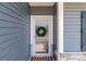 Close-up of a blue home's front door with a wreath and white trim, complemented by a black doormat at 2022 Mcdonald Dr, Stanfield, NC 28163