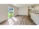 Bright living room with vinyl plank flooring, glass doors, and view to back yard and kitchen with white cabinets at 2106 Columbidae Ln, Gastonia, NC 28052
