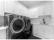 Modern laundry room with gray, front-load washer and dryer, white cabinets, countertop, and matte black hardware at 3933 Ayrshire Pl, Charlotte, NC 28210