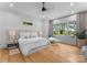 Bright bedroom showcasing a large bed, wood floors, a ceiling fan, and natural light from windows at 3933 Ayrshire Pl, Charlotte, NC 28210